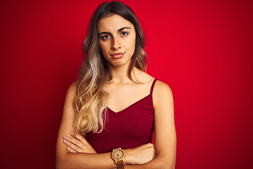 Young beautiful woman wearing a t-shirt over red isolated background skeptic and nervous,...