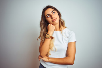 Young beautiful woman wearing casual white t-shirt over isolated background with hand on chin thinking about question, pensive expression. Smiling with thoughtful face. Doubt concept.