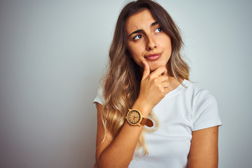 Young beautiful woman wearing t-shirt over white isolated background serious face thinking about...