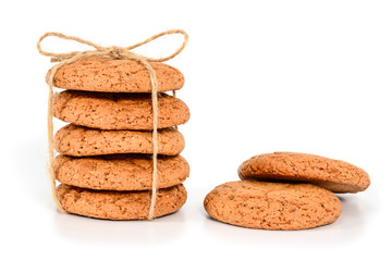 Homemade cookies. Five sweet cookie made from oatmeal flour, stacked and tied with linen rope in rustic style and two next. Tasty biscuit in high resolution closeup isolated on white background.
