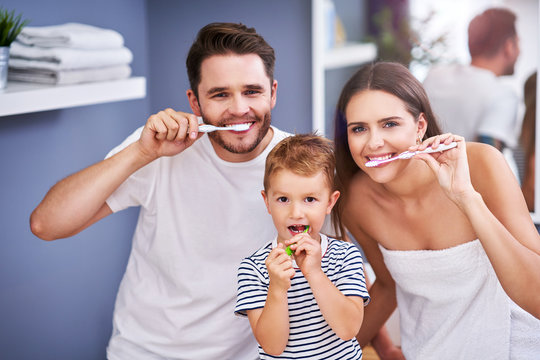 Portrait of happy family brushing teeth in the bathroom