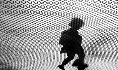 Blurry  shadow silhouette of one women walking on a tiled street sidewalk