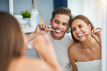 Portrait of happy young couple brushing teeth in the bathroom