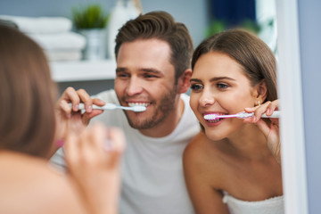 Portrait of happy young couple brushing teeth in the bathroom