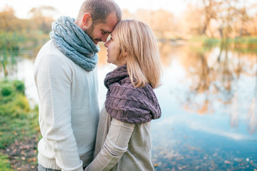 Loving couple in knitted clothes romantic portrait with reflected lake on background.