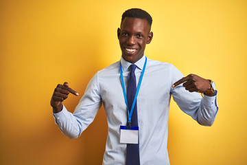 African american businessman wearing identification card over isolated yellow background looking...