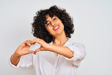 Young arab woman with curly hair wearing casual shirt over isolated white background smiling in love showing heart symbol and shape with hands. Romantic concept.