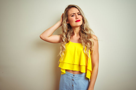 Young beautiful woman wearing yellow t-shirt standing over white isolated background confuse and wonder about question. Uncertain with doubt, thinking with hand on head. Pensive concept.