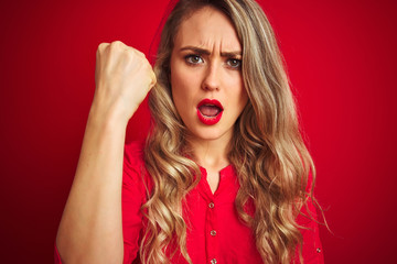 Young beautiful woman standing over red isolated background annoyed and frustrated shouting with anger, crazy and yelling with raised hand, anger concept