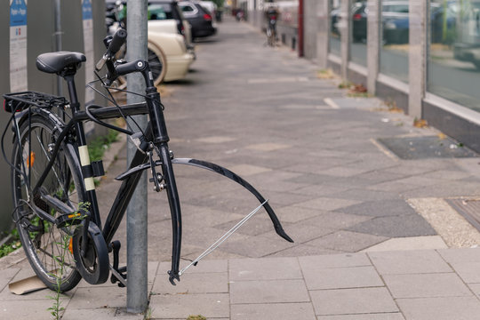 Bike or bicycle lock on steel pole on sidewalk was stolen its front wheel. Stolen wheel bicycle. Abandon vintage bicycle leave on street in Europe.