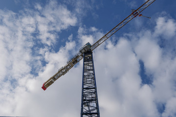 Low angle view under tower crane against blue sky and cloud.