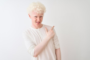 Young albino blond man wearing casual t-shirt standing over isolated white background cheerful with a smile of face pointing with hand and finger up to the side with happy and natural expression