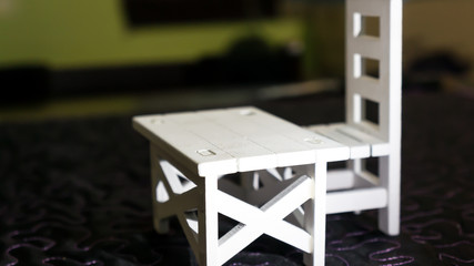 Miniature white table and chair on the black textured background