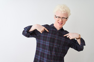 Young albino blond man wearing casual shirt and glasses over isolated white background looking confident with smile on face, pointing oneself with fingers proud and happy.