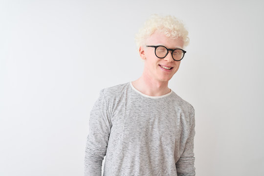 Young albino blond man wearing striped t-shirt and glasses over isolated white background winking looking at the camera with sexy expression, cheerful and happy face.