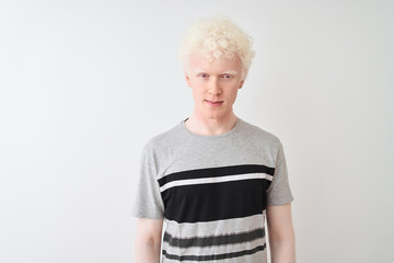 Young albino blond man wearing casual t-shirt standing over isolated white background with serious...
