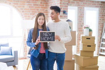 Fototapeta na wymiar Young beautiful asian couple smiling happy holding blackboard with new home text, hugging in love moving to a new house