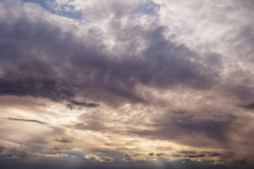 Obraz premium Beautiful dramatic stormy sky and cloud before sunset with god light. Orange, purple and golden light beam with sun rays between cumulonimbus cloudscape. 