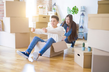 Fototapeta na wymiar Funny asian couple having fun, riding inside cardboard box smiling happy, very excited moving to a new house