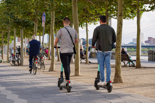 People ride E-scooters, trendy urban transportation with Eco friendly sharing  mobility concept, and bicycle on bicycle lane at promenade riverside of Rhine River in Düsseldorf, Germany.