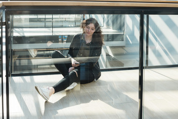 Female student sitting in a glass corridor in a modern campus building