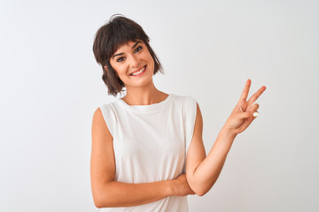 Fototapeta premium Young beautiful woman wearing casual t-shirt standing over isolated white background smiling with happy face winking at the camera doing victory sign. Number two.