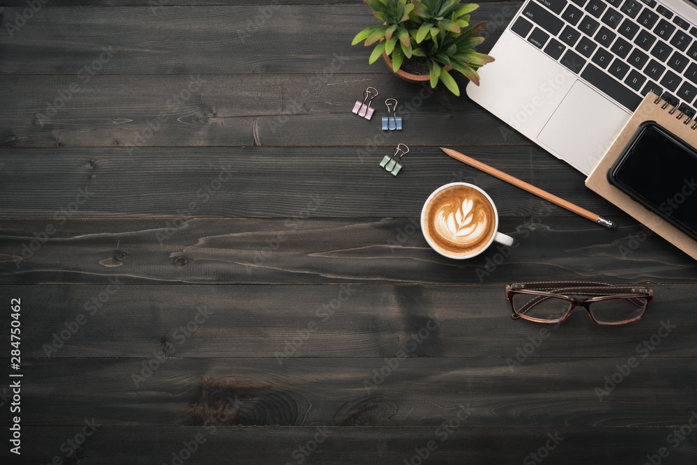 Poster modern dark wood office desk table with laptop, smartphone and other supplies with cup of coffee. co