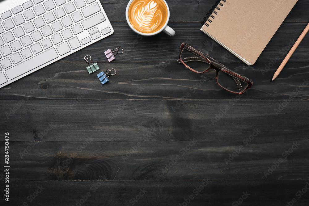 Poster modern dark wood office desk table with keyboard and other supplies with cup of coffee. copy space f