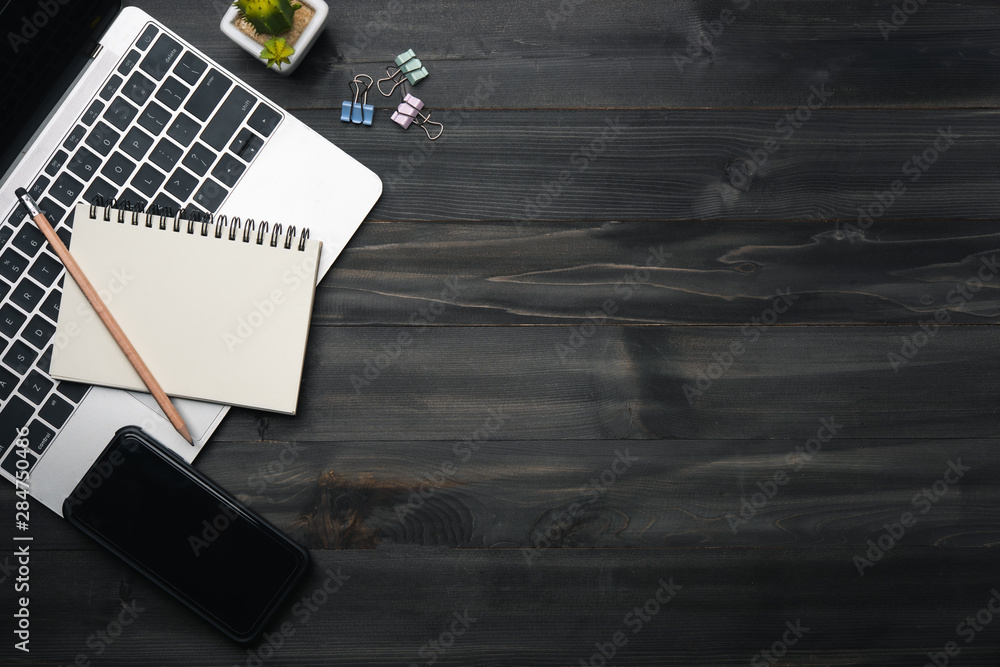 Poster modern dark wood office desk table with laptop, smartphone and other supplies. copy space for input 