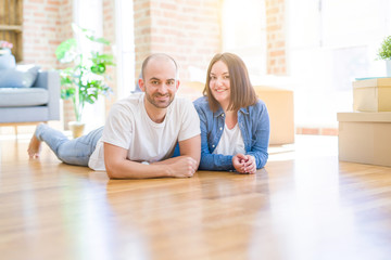 Obraz premium Young couple in love lying on the floor of new house arround cardboard boxes, smiling very happy for moving to a new apartment