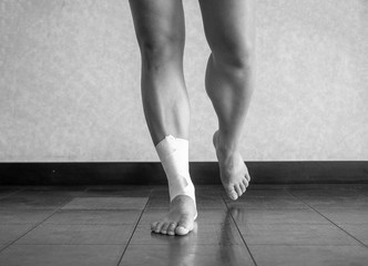 Black and white version of Athlete balancing on a recovering ankle sprain with an ankle tape job