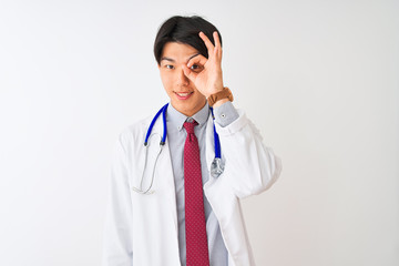 Chinese doctor man wearing coat tie and stethoscope over isolated white background doing ok gesture with hand smiling, eye looking through fingers with happy face.