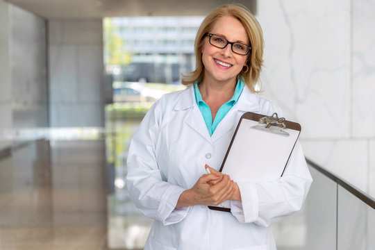 Likable warm and friendly doctor physician, healthcare professional portrait, smiling sincere with clipboard at hospital clinic