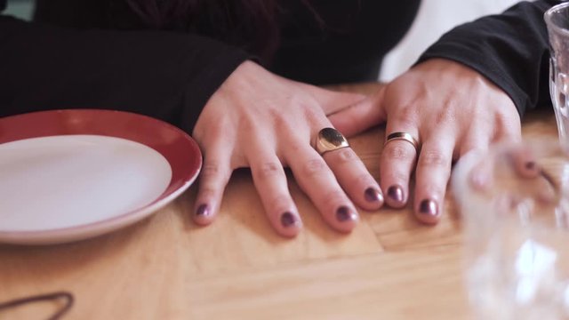 Video of woman's hands fidgeting on a table.  Painted fingernails.