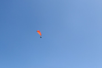 Powered paragliding - paraglider with red parachute against a blue sky.