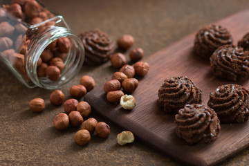 Chocolate mini-cakes and hazelnuts on a rusty metal surface. Sweets and nuts