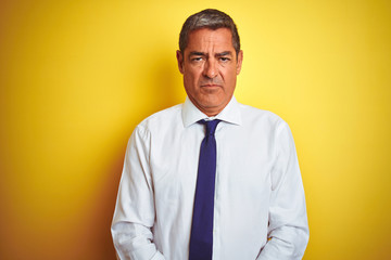 Handsome middle age businessman standing over isolated yellow background depressed and worry for distress, crying angry and afraid. Sad expression.