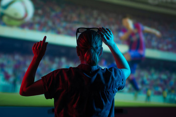 The girl is watching football, soccer in 3D, with glasses on the big screen. with entertainment and...