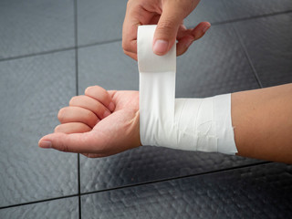 Black and white version of Athlete taping her wrist for injury and support 