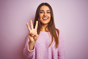 Young beautiful woman wearing casual sweater standing over isolated pink background showing and...