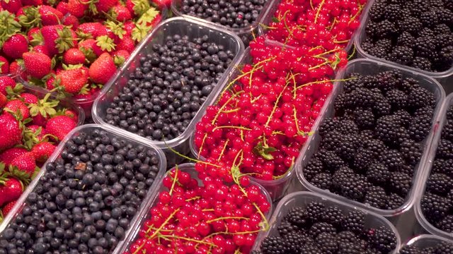 Fruits: strawberries, blackberries, red currants, raspberries in special trays on the counter in the supermarket