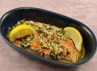 Dinner dish for two of salmon fish fillets with nuts and lemon in blue baking dish