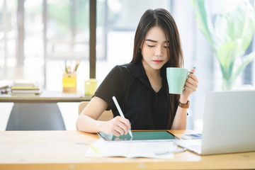 Young Asian graphic designer working on computor and graphics tablet in her working space