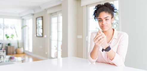 Wide angle of beautiful african american woman with afro hair Suffering pain on hands and fingers,...