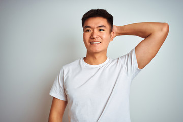 Obraz premium Young asian chinese man wearing t-shirt standing over isolated white background smiling confident touching hair with hand up gesture, posing attractive and fashionable