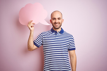 Naklejka premium Young man holding speech bubble with blank space for message over pink isolated background with a happy face standing and smiling with a confident smile showing teeth