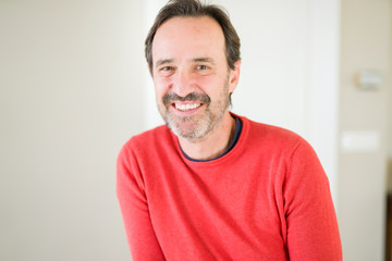 Obraz premium Handsome middle age man smiling looking at the camera at home