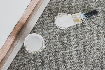 tin of white paint or primer with brush next to sanded wooden skirting boards