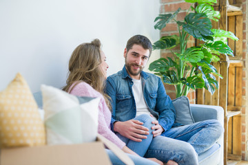 Obraz premium Young couple in love hugging sitting on the sofa very happy moving to a new home