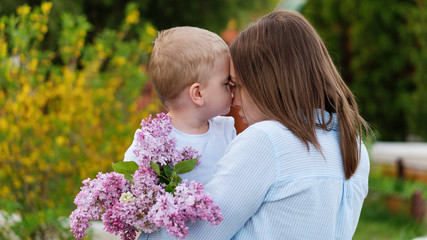 Young loving mother walking with her little son on spring background. Cute child and her mom on...